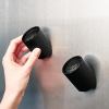 Hand placing black magnetic cup on metal surface.