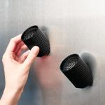 Hand placing black magnetic cup on metal surface.