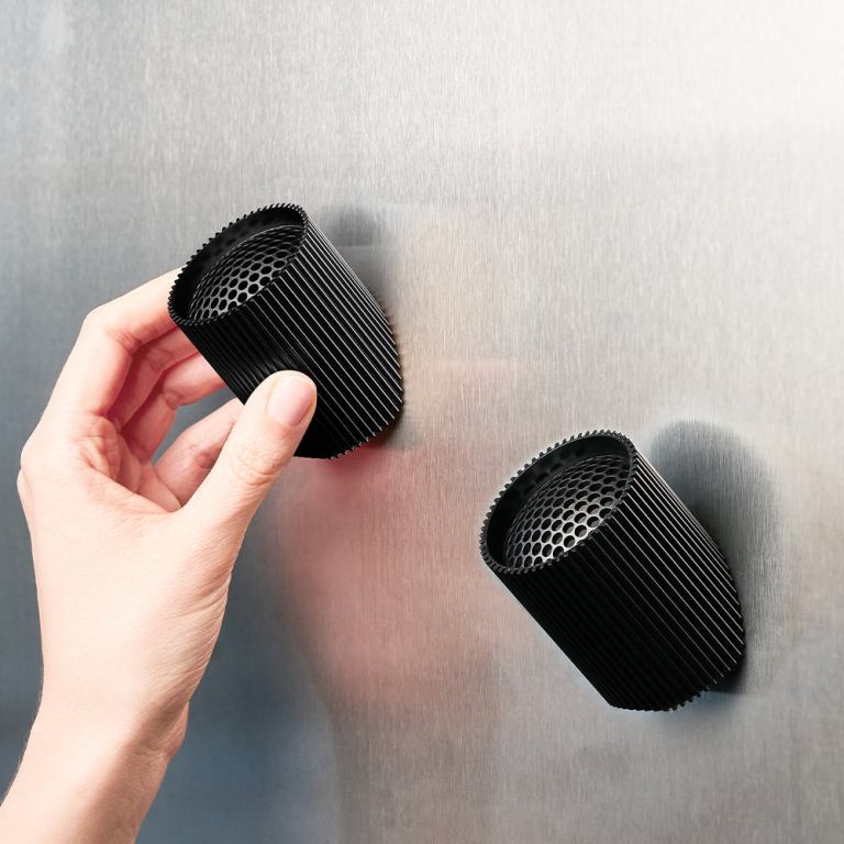 Hand placing black magnetic cup on metal surface.