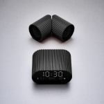 Modern black digital clock on grey background.