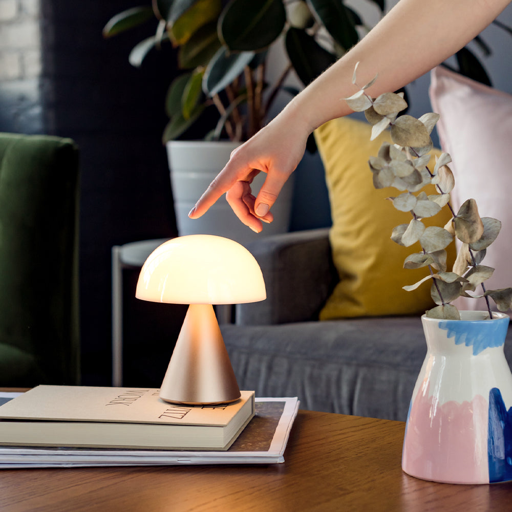 Finger pointing at glowing table lamp indoors.