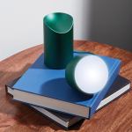 Spherical lamp on stacked blue books, wooden table.