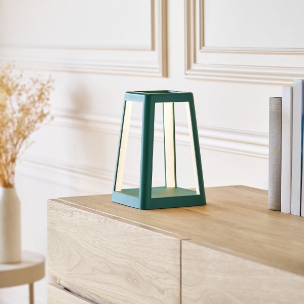 lexon lantern portable lamp with built in wireless charger green Modern triangular teal lamp on wooden cabinet.