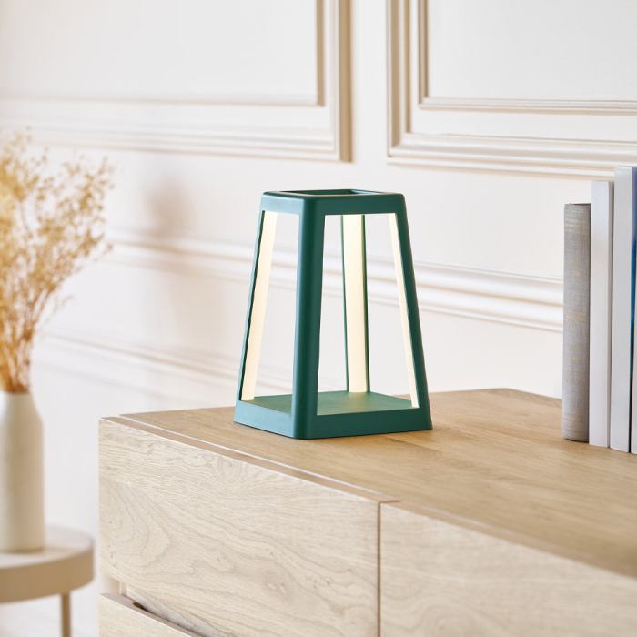 Modern triangular teal lamp on wooden cabinet.