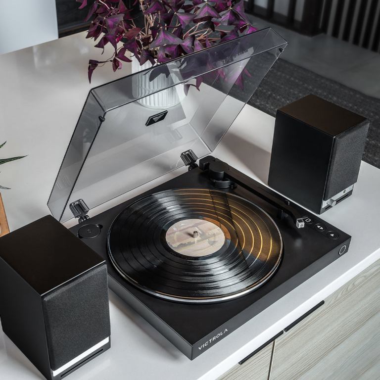 Modern turntable playing vinyl record with speakers.