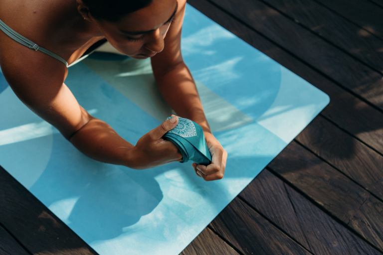 Woman practising yoga stretching on blue mat