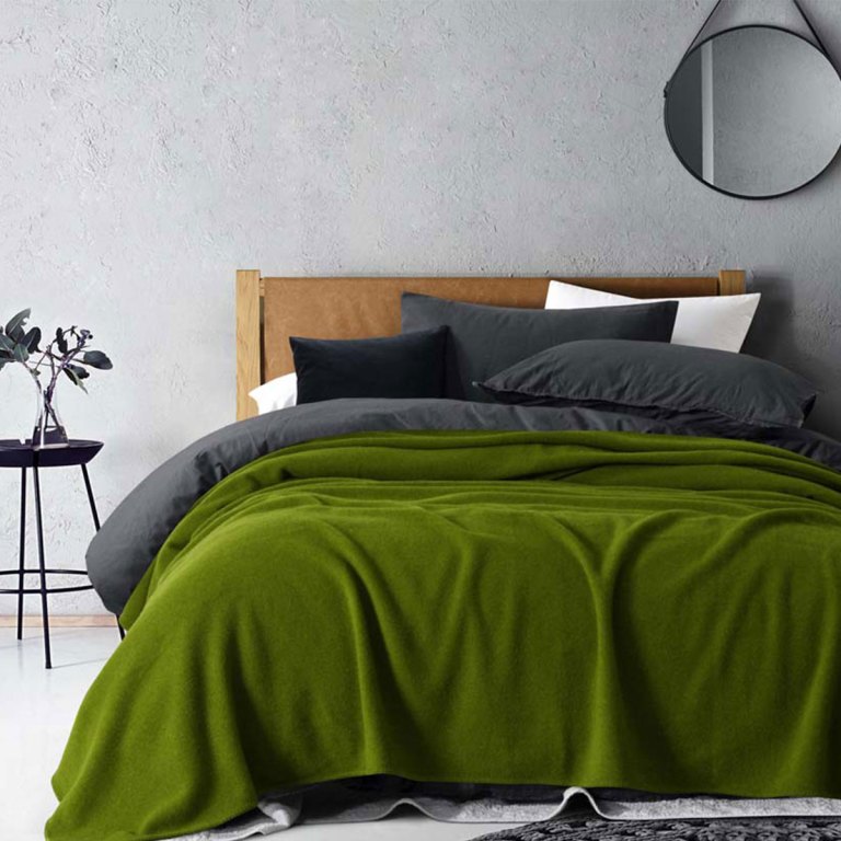Stylish bedroom with green blanket and modern decor.