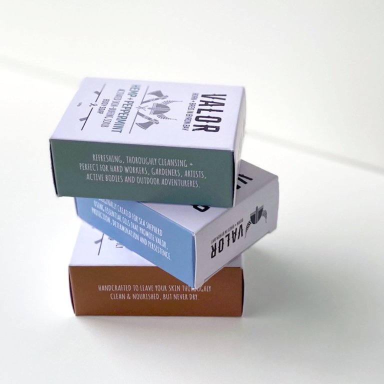 Three stacked boxes of organic soap on white surface.
