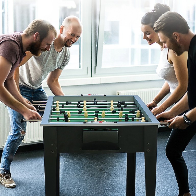 Friends enjoying a game of foosball indoors.