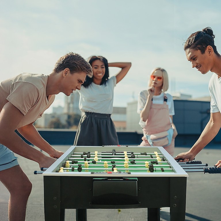 Friends playing table football outdoors on rooftop