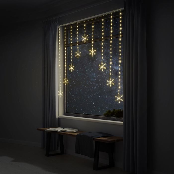 led snowflakes curtain lights avialable in 2 colors cool white Snowflake string lights decorating a window.