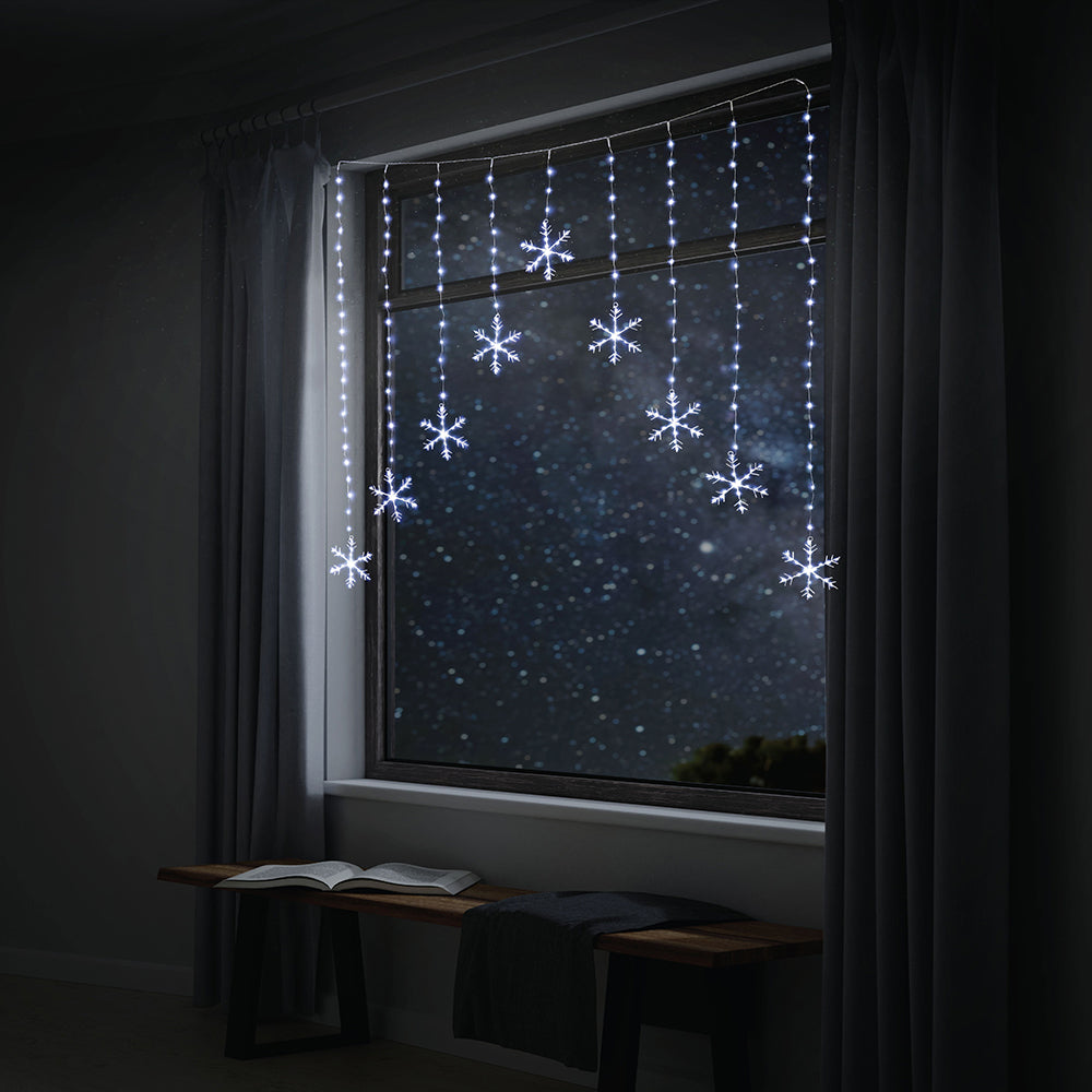Snowflake fairy lights on window at night.