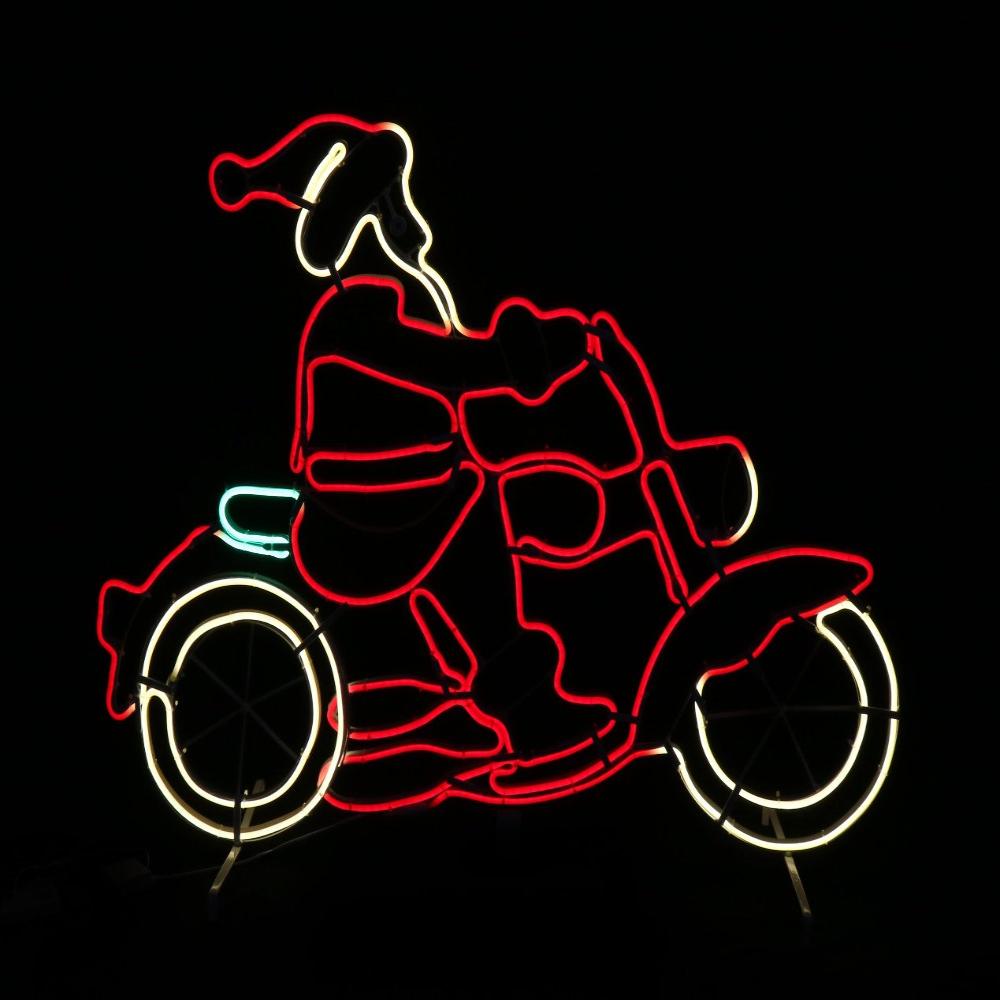 Neon Santa riding a motorcycle at night.
