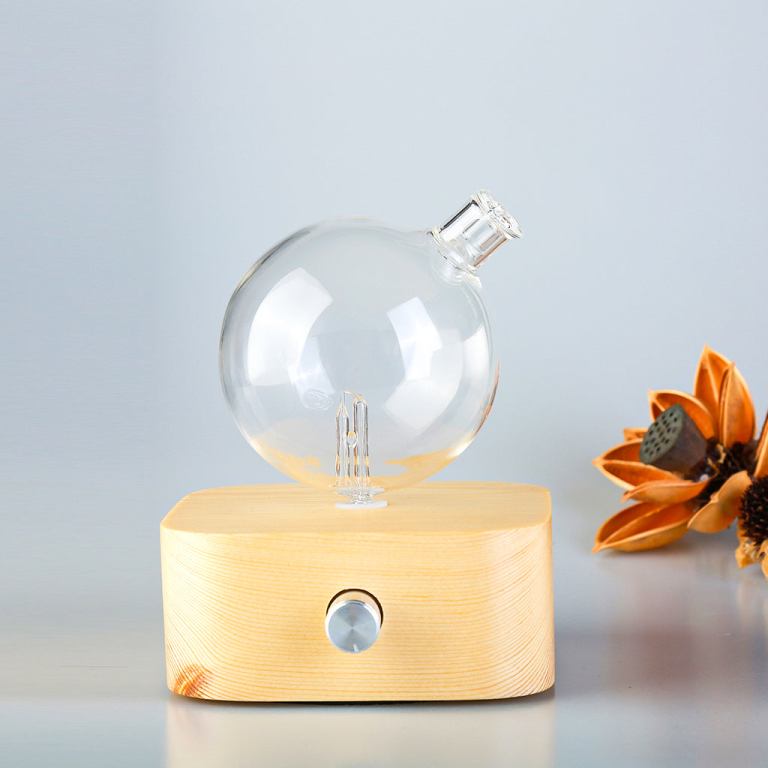 Glass essential oil diffuser with wooden base.