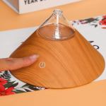 Person touching wooden aroma diffuser power button.