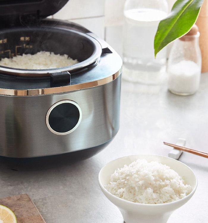 Rice cooker steaming rice beside filled bowl