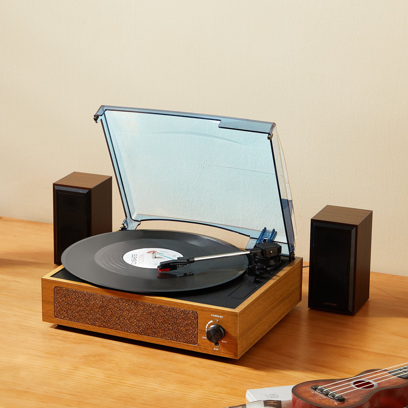 Wooden turntable playing vinyl record with speakers.