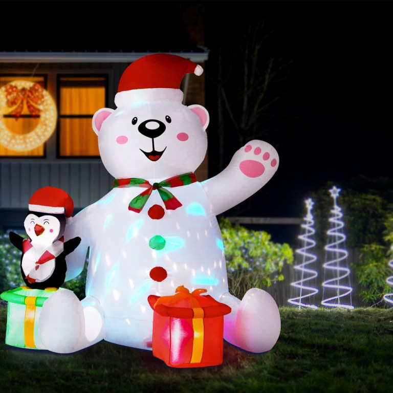 Christmas inflatable bear with penguin and presents outdoors.