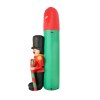 Inflatable nutcracker decoration beside green tree.