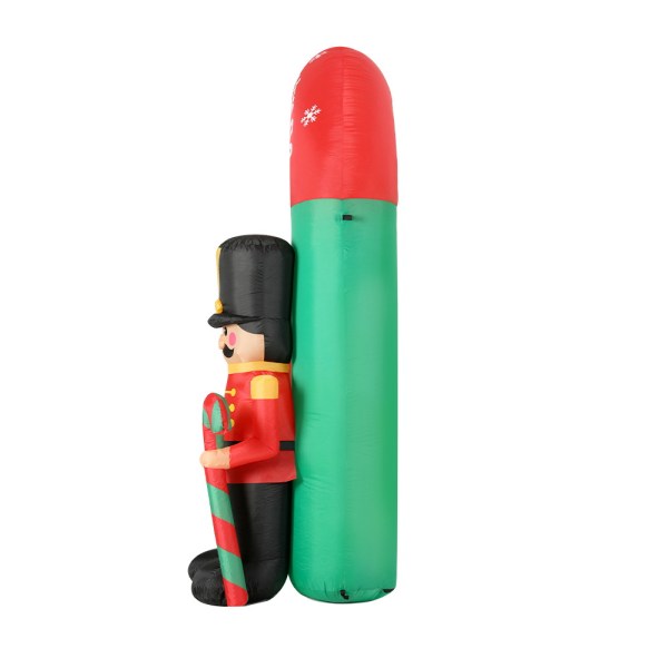 Inflatable nutcracker decoration beside green tree.