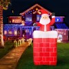 Inflatable Santa in chimney, festive house lights.