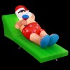 Inflatable Santa lounging on green sunbed, summer theme