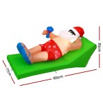 Inflatable Santa lounging on green beach chair.