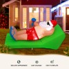 Inflatable Santa lounging on green chair in yard.