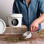 plant science moulinomega 2.jpg Person scooping herb blend from container onto table.