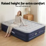 Woman sitting on raised air mattress, smiling.