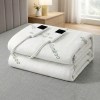 Folded bamboo electric blanket with controls on bed.