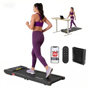 Woman using compact treadmill while working at desk.