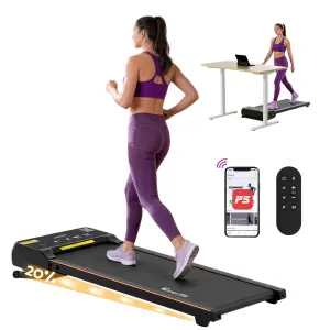 Woman using treadmill with desk, phone, and remote.