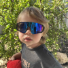 Child wearing large blue sunglasses outdoors.