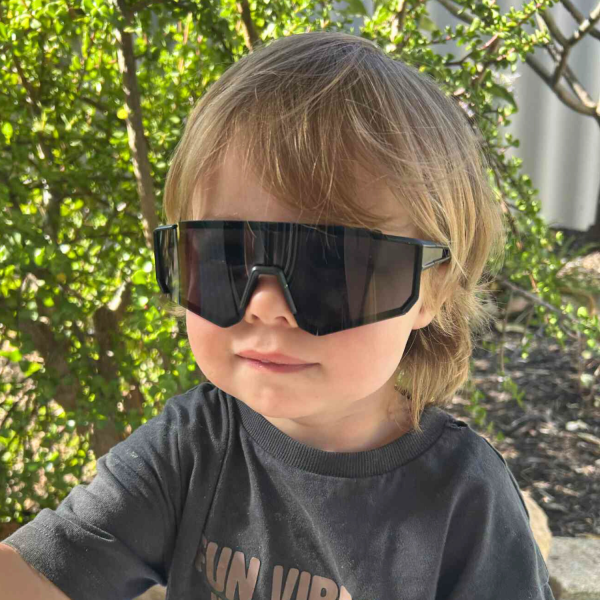 sportiq jnr kids jet black Child wearing oversized sunglasses in garden