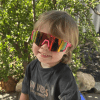 Child smiling with colourful sunglasses outdoors.