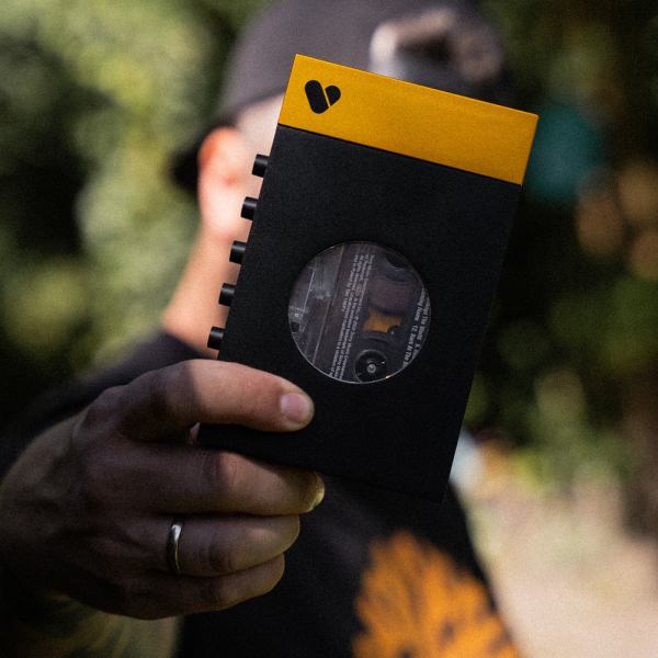 Person holding a yellow and black device outdoors.