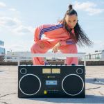 Woman in pink tracksuit with boombox outdoors.