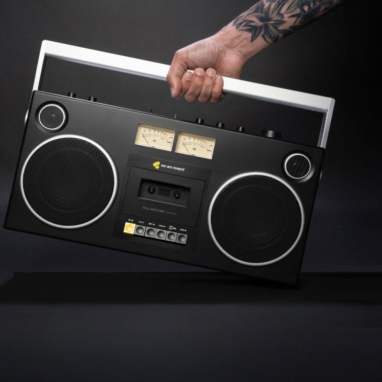 Tattooed hand holding vintage portable radio.