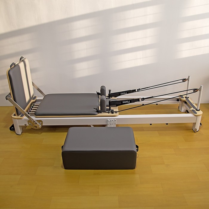 folding pilates reformer machine – home workout bed for full body fitness training Pilates reformer machine on wooden floor.