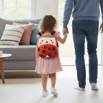 Child with ladybug backpack holding adult’s hand