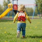 Toddler with ladybug backpack running to playground