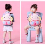 Toddler with cute cartoon backpack on pink background