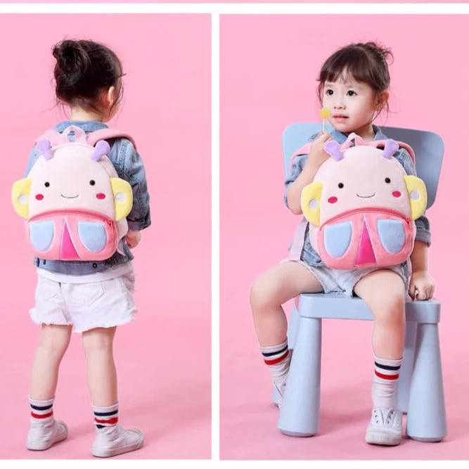 Toddler with cute cartoon backpack on pink background