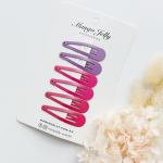 Purple and pink snap hair clips on card