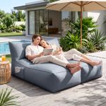 Couple relaxing poolside with tablet at modern home