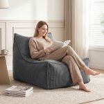Woman reading book on cushioned chair by window