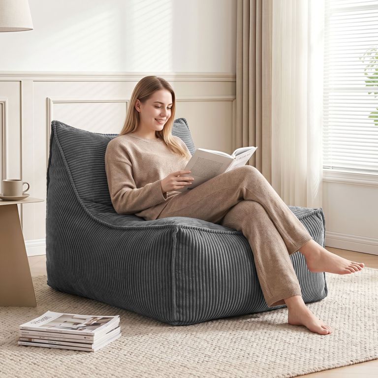 Woman reading book on cushioned chair by window