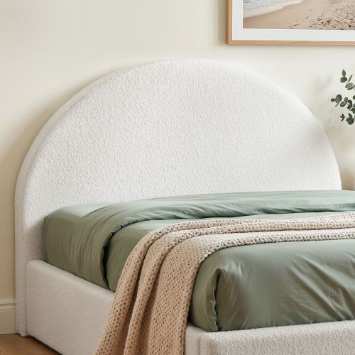 Curved upholstered bed with sage green bedding