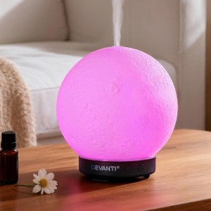 Pink glowing essential oil diffuser on wooden table